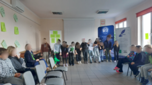 Kilku uczniów stoi na przedzie sali dydaktycznej.