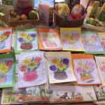 Kartki-kolorowanki w otoczeniu ozdób wilekanocnych.