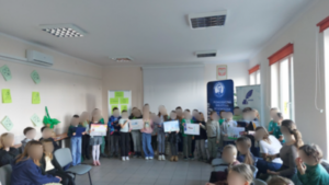Grupa dzieci pozuje z pracami plastycznymi w rękach.