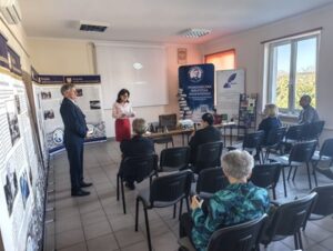 Kobieta w czerwonej spódnicy i mężczyzna w garniturze stoją przed publicznością,
