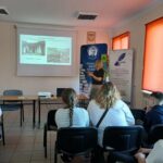 Dwie osoby w białych koszulkach siedzą na krzesłach.