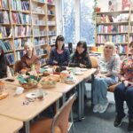 Kilka kobiet siedzi wokół stołu z przekąskami.