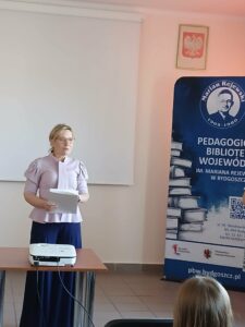 Kobieta w jasnej koszuli trzyma plik kartek.
