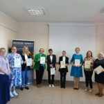 W półkolu stoi grupa osób, trzymając kartki.