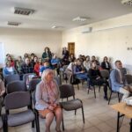 Ludzie w różnym wieku siedzący w sali wykładowej.