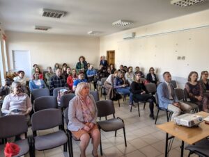 Ludzie w różnym wieku siedzący w sali wykładowej.