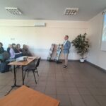 Mężczyzna w niebieskiej marynarce mówi do siedzącej publiczności.