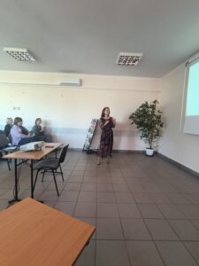 Kobieta w sukience w kwiaty przemawia do publiczności.