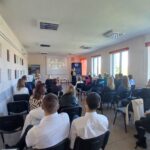 Sala audytoryjna fotografowana od tyłu - widać plecy siedzących.