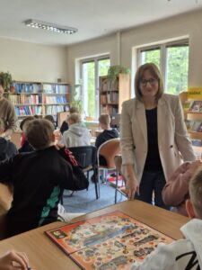 Młodzież siedzi przy stolikach z grami planszowymi.