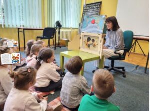 Dzieci słuchają opowieści w teatrzyku kamishibai.