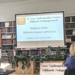 Ekran z wyświetloną prezentacją. W tle regały z książkami i kwiaty.