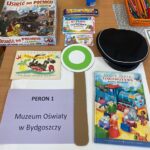 Ułożone na stole: czapka kolejarza, lizak, gra planszowa, książka i dyplom.