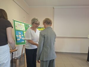 Kobieta w białej bluzce wręcza nagrodę chłopcu w szarym garniturze.