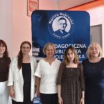 Pięć kobiet pozuje do zdjęcia na tle niebieskiej tablicy instytucji.