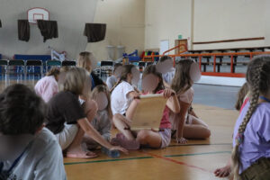 Grupka dziewcząt przygląda się zwojowi w ręce jednej z nich.