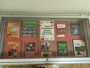 Wybrane książki ustawione w gablocie na czerwonym tle.