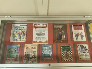 Kilka książek w gablocie na czerwonym tle.
