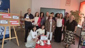 Grupa osób pozuje przy stoliku ze świecami i logo Narodowego Czytania "Dziady" 2026