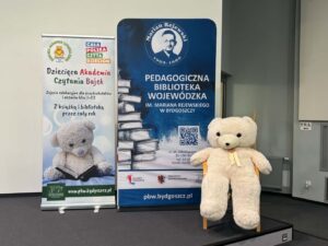 Duży biały miś, obok niebieski i biały baner.